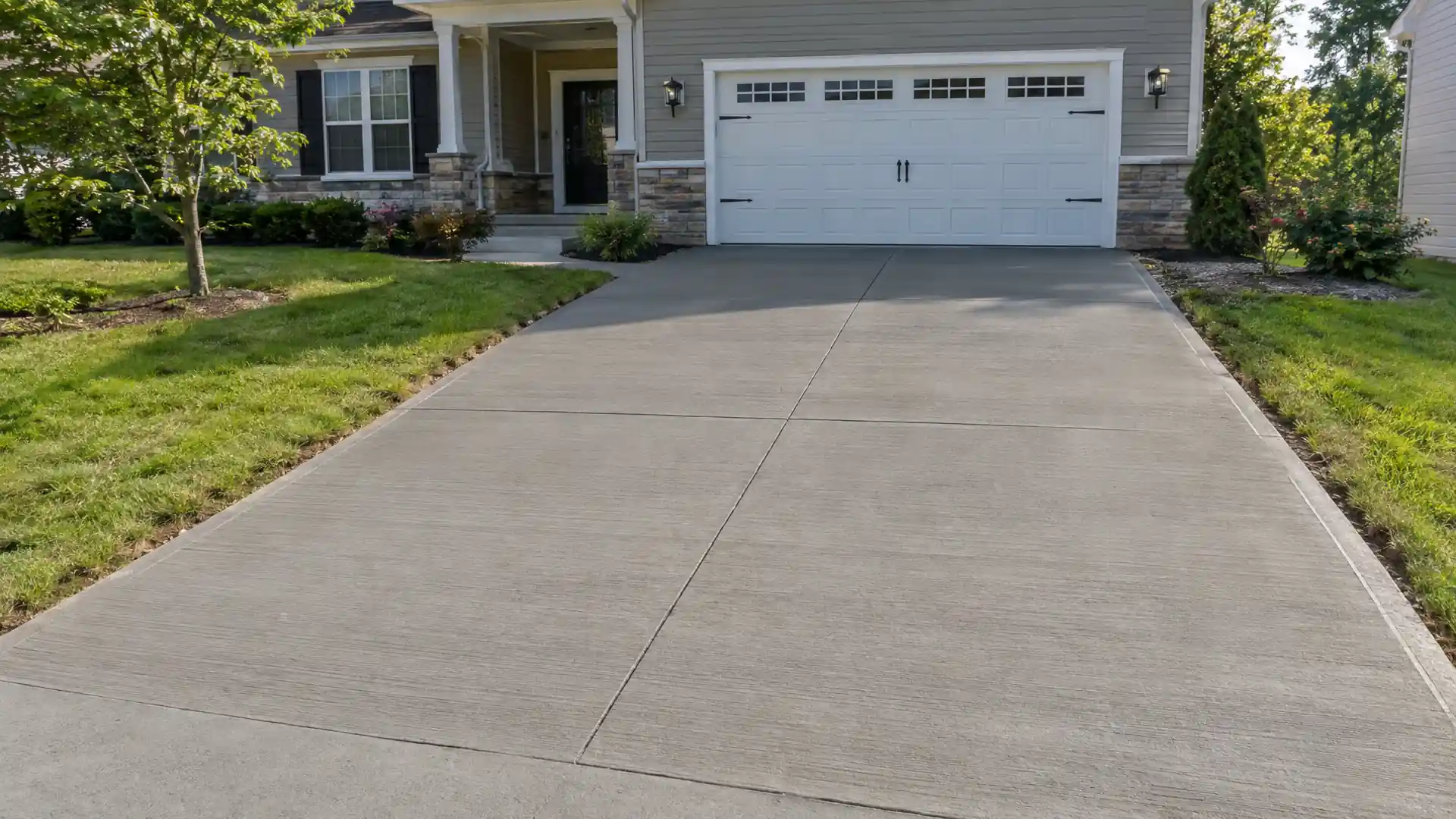 Long new concrete driveway between lawns leading to a garage